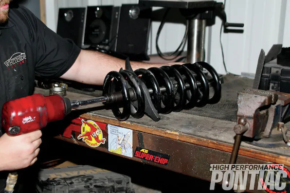 18. Before installing the replacement coilspring and replacing the shock absorber, the front springs need to be compressed in order to fit. Mike installed a coilspring compressor and used a 19mm socket and impact gun to compress the spring down to 13 inches (uncompressed was 15 inches).