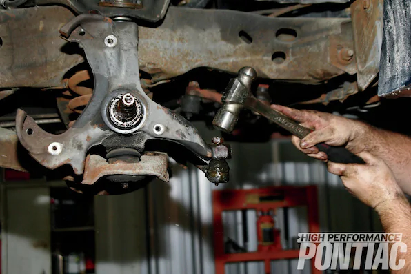 8. Disassembly continues with the removal of the outer-tie-rod ends. After pulling the cotter key, the 3&frasl;4-inch castle nut is loosened but not removed. A dead-blow sledgehammer is used to pound the top of the nut and underside of the tie rod until it unseats from the spindle. Although the tie-rods were both in good shape, replacement is necessary after this disassembly method. We sourced heavy-duty replacements from PTFB.