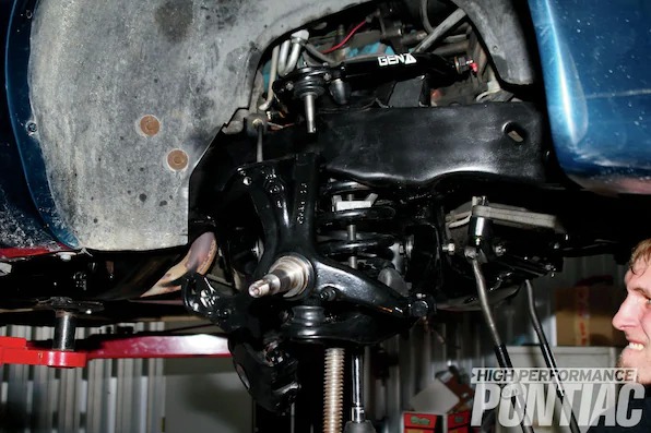 19. He set up a pole jack under the lower control arm and made sure he had the two castle nuts (one for the lower-control-arm ball joint and a second for the upper control arm to spindle). Then he installed the spindle and put the castle nut on a few turns, installed a new spring isolator on the top of the spring, got the spring in position, and slowly raised the lower control arm until he could secure the castle nut on the top of the spindle. Afterwards, he removed the coilspring–compressor tool and tightened up the ball joints to specifications.