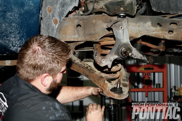 12. Mike slowly and carefully lowered the screw jack to release the pressure on the front coil spring. Unfortunately, after the pressure was completely off of the control arm, the spring was stuck.