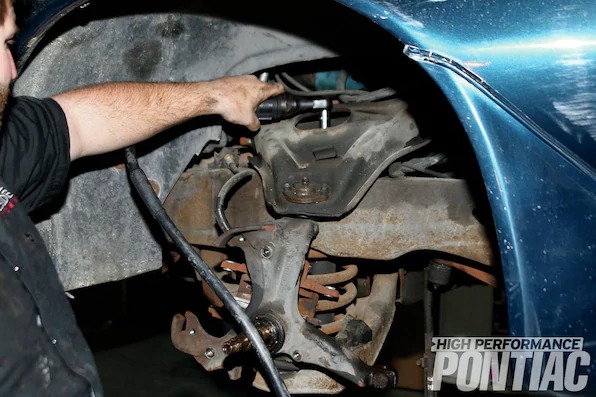 9. To remove the top nut holding the shock absorber on, we used a 9⁄16-inch socket. If the nut spins (which can sometimes be the case), snake some locking pliers onto the upper rod of the shock and remove the nut and washer.